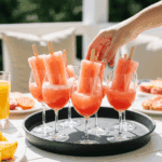 A tray of Frosé Ice Pops in wine glasses being served at a party.