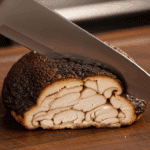 A knife slicing through the cooked Lion's Mane Mushroom Steak, showing the meaty interior.