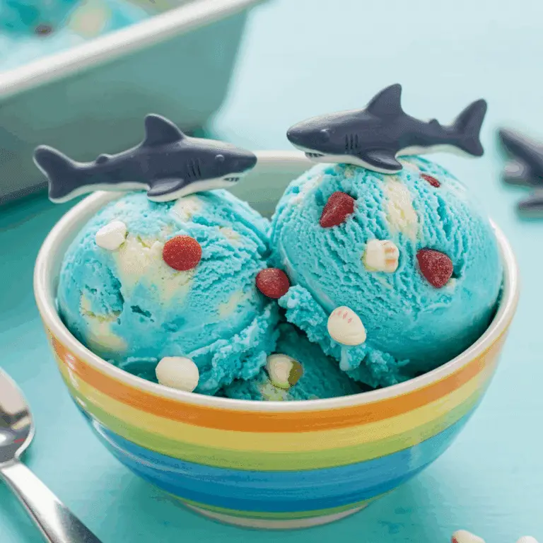A bowl of homemade No-Churn Shark Ice Cream decorated with gummy sharks.