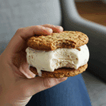 A hand holding an Oat Milk and Oatmeal Cookie Ice Cream Sandwich with a bite taken out.