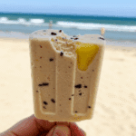 A hand holding a Cocoa Colada Ice Pop with a bite taken out to show the texture.