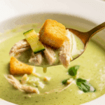 A spoonful of the finished Chilled Zucchini Soup with chicken and a crouton.