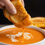 Dipping a grilled cheese sandwich into a bowl of Creamy Tomato Soup.