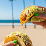 Two hands holding delicious, freshly assembled Fish Tacos.