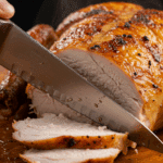 A knife slicing into the juicy, finished Spatchcock Cornish Hen.