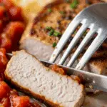 A fork cutting into a juicy, finished Greek Pork Chop.