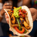 A hand holding a finished, assembled Grilled Chicken Fajita.