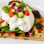 A perfect slice of the finished Grilled Salad Pizza with burrata.