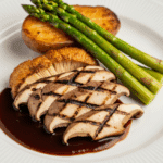 A plated meal of sliced Lion's Mane Mushroom Steak with grilled asparagus.