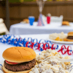 A serving of Loaded Baked Potato Salad on a plate at a 4th of July cookout.