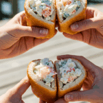 Two hands holding finished Monkfish "Lobster" Rolls.