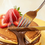 A fork cutting into a Nutella Stuffed Pancake, revealing the gooey center.