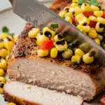 A knife slicing into the juicy, finished Pan-Seared Pork Chop.