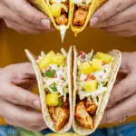 Two hands holding finished Pineapple Chicken Tacos.