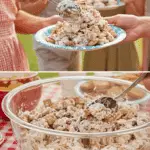 Serving a large scoop of Cookie Salad from a bowl at a summer potluck.