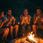 A happy group of friends eating gooey, delicious s'mores around a campfire.