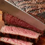 A knife slicing through a perfectly cooked medium-rare steak.