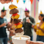 Dipping a finished Steak and Potato Kebab into a bowl of dipping sauce.