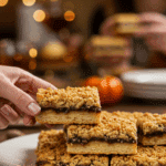 A beautiful platter of homemade, multi-layered Thanksgiving Pie Bars being served at a festive holiday party.