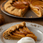 An elegant slice of homemade Apple-Pumpkin Galette being served with a quenelle of mascarpone at a dinner party.