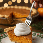 A perfect slice of homemade Maple Bourbon Sweet Potato Pie with a dollop of whipped cream being served for a holiday dessert.