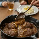 The finished skillet of homemade Salisbury Steak and gravy being served at a cozy family dinner.