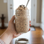A hand holding a jar of High-Protein Cookie Dough Overnight Oats for a healthy grab-and-go breakfast.