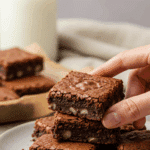 A hand taking a delicious, fudgy, homemade Cottage Cheese Brownie from a plate.