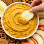 A beautiful platter with a bowl of Pumpkin Dip in the center, surrounded by a variety of cookies, fruits, and pretzels for dipping.