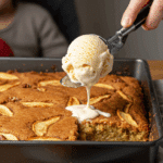 Serving a warm square of the homemade Easy Apple Cake with a large scoop of butter pecan ice cream.