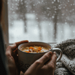 A person holding a warm, steaming mug of Ham and Split Pea Soup on a cold day.