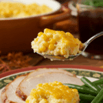 A delicious scoop of homemade Instant Pot Corn Pudding being served on a plate at a holiday dinner.