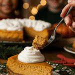 A beautiful slice of Instant Pot Pumpkin Cheesecake with a swirl of whipped cream being served for a holiday dessert.