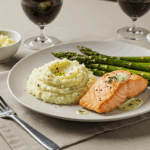 An elegant dinner plate with a perfect scoop of creamy mashed potatoes served next to a seared salmon fillet.