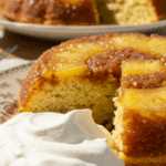 A perfect slice of homemade Pineapple Upside-Down Cake with a dollop of whipped cream being served at a family gathering.