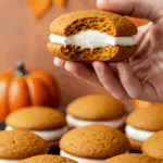 A hand holding a delicious, homemade Pumpkin Whoopie Pie at a fun fall party.