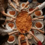 A happy family enjoying a large platter of pasta with homemade Sunday Pasta Sauce at a family dinner