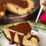 A perfect slice of homemade, no-bake Peanut Butter Pie with hot fudge sauce being served at a party.