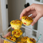 A hand grabbing two Cottage Cheese Egg Bites for a quick and easy grab-and-go breakfast.