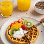 A person enjoying a healthy breakfast of High-Protein Cottage Cheese Waffles topped with fruit and yogurt.