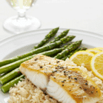 A healthy dinner plate with a serving of homemade, Broiled Haddock with lime-cilantro butter, served with rice and asparagus.