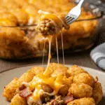 A cozy plate of homemade, cheesy Bacon Cheeseburger Tater Tot Casserole being served for a family dinner.