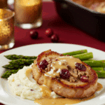 An elegant plate of a homemade, Cranberry-Stuffed Pork Chop with a creamy pan sauce, served with mashed potatoes for a holiday dinner.