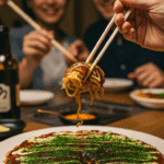 A beautiful plate of homemade, authentic Okonomiyaki being enjoyed with chopsticks at a fun and casual dinner.