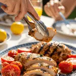 A beautiful platter of homemade Grilled Basil Chicken being served at a sunny, outdoor dinner party.
