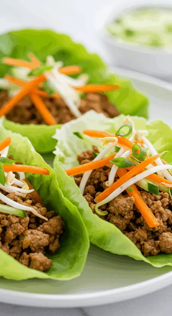A beautiful, rustic platter of three homemade, healthy, and fresh Asian Lettuce Wraps, filled with a savory turkey filling and topped with crunchy vegetables.