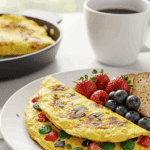 An elegant plate of a homemade, fluffy Mediterranean Omelet being served for a healthy weekend brunch with fresh fruit and coffee.