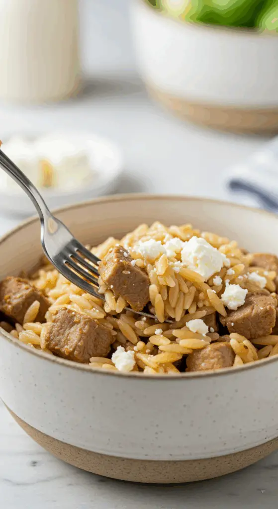 A beautiful bowl of homemade, healthy Pork and Orzo with feta being served for a delicious weeknight dinner.