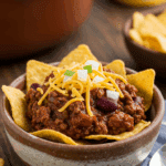 A delicious bowl of homemade Texas Chili being served as a classic "Frito Pie" at a fun game day party.