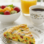 An elegant plate of a homemade, fluffy Spinach Frittata being served for a healthy weekend brunch with fresh fruit and coffee.